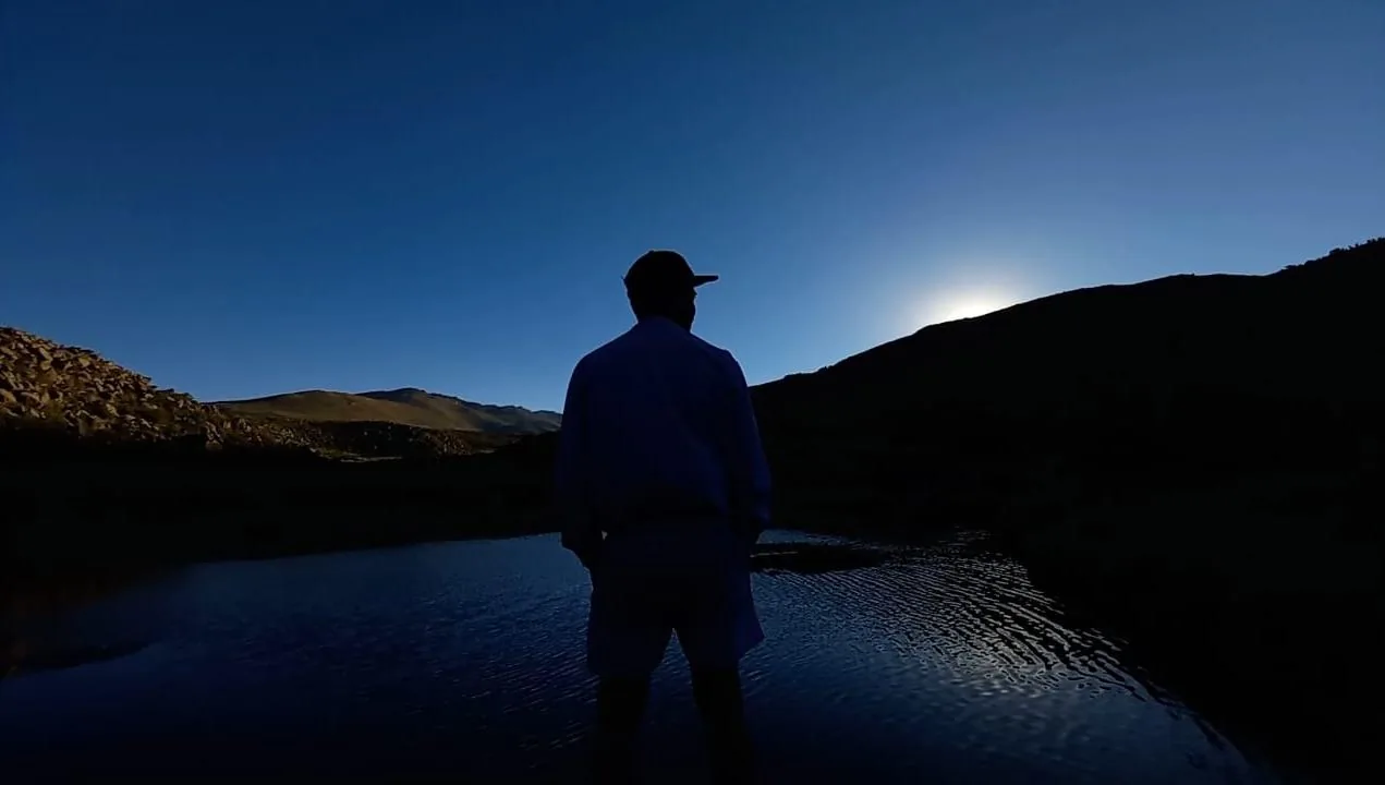 Silueta de una persona junto a la laguna al caer la noche, en el campo